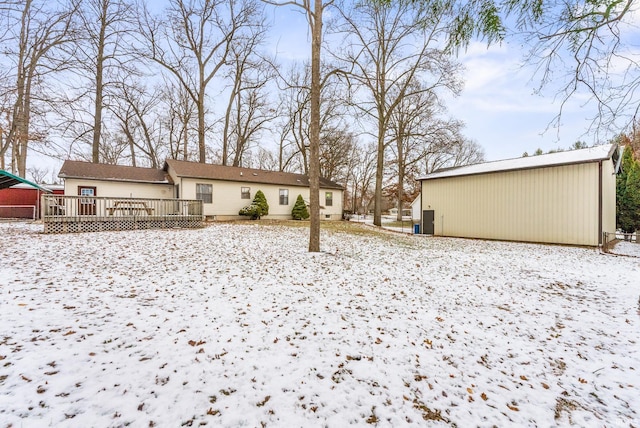 snowy yard featuring an outbuilding and a wooden deck