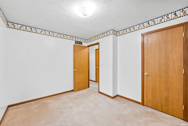 carpeted empty room with a textured ceiling