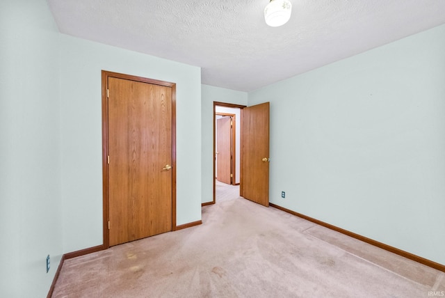 unfurnished bedroom with light carpet, a textured ceiling, and a closet