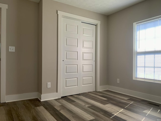 unfurnished bedroom with dark hardwood / wood-style floors and a closet