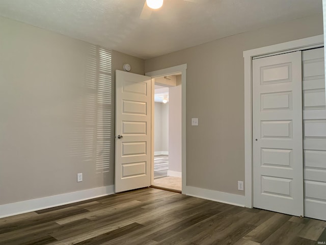 unfurnished bedroom with ceiling fan, a closet, and dark hardwood / wood-style floors