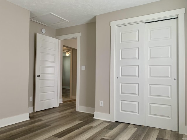 unfurnished bedroom featuring a textured ceiling, a closet, and dark wood-type flooring