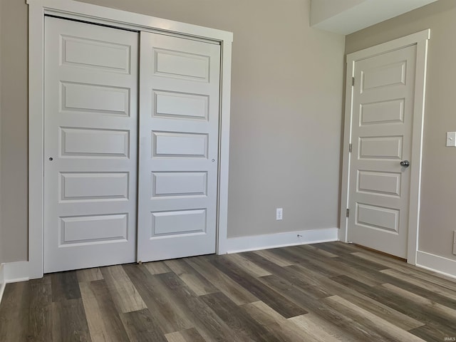 unfurnished bedroom with dark hardwood / wood-style flooring and a closet