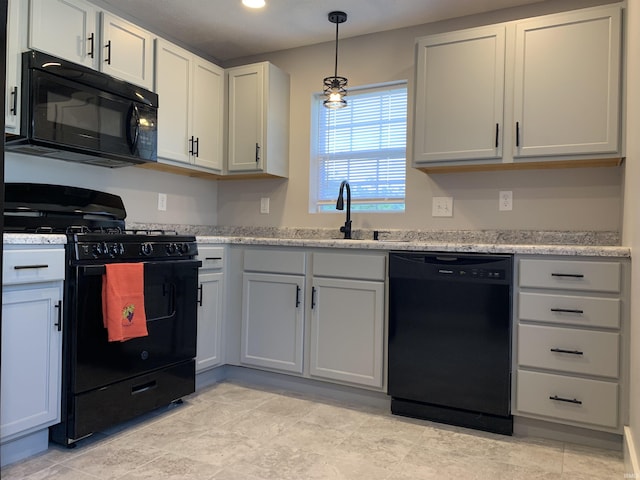 kitchen with light stone countertops, sink, white cabinets, and black appliances