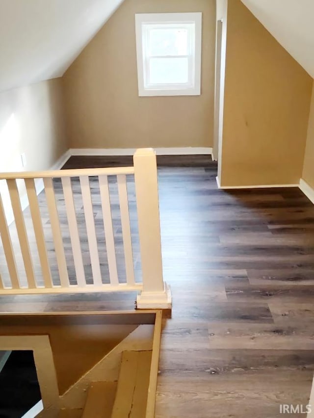 additional living space with hardwood / wood-style floors and vaulted ceiling