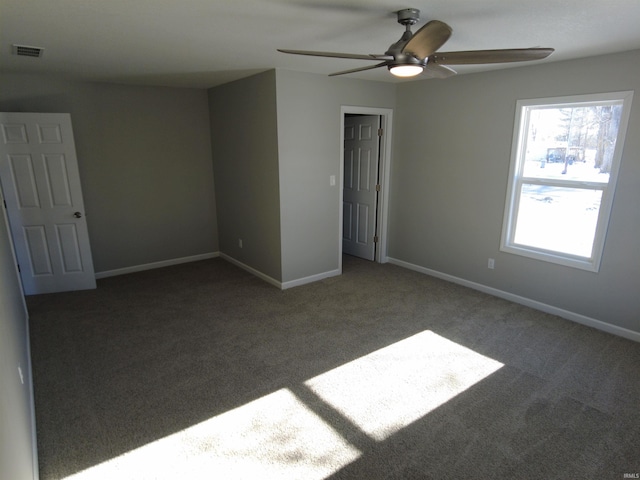 empty room with ceiling fan and dark carpet