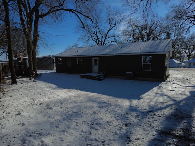 snow covered back of property featuring central AC