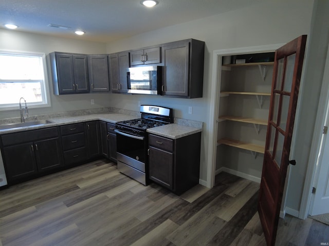 kitchen featuring hardwood / wood-style flooring, sink, light stone counters, and appliances with stainless steel finishes