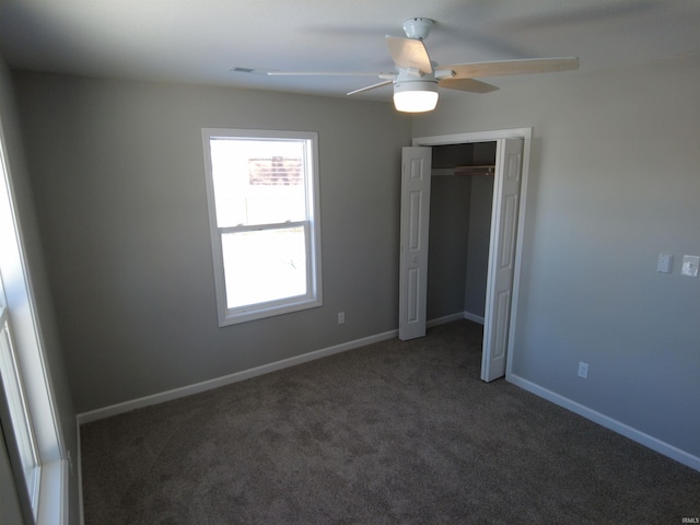 unfurnished bedroom with ceiling fan, a closet, and dark colored carpet