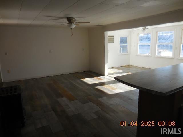 unfurnished living room featuring ceiling fan and dark hardwood / wood-style floors