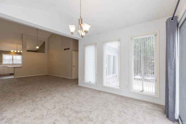 unfurnished room featuring light carpet, a chandelier, and vaulted ceiling