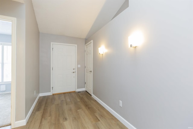 corridor featuring light hardwood / wood-style flooring and lofted ceiling