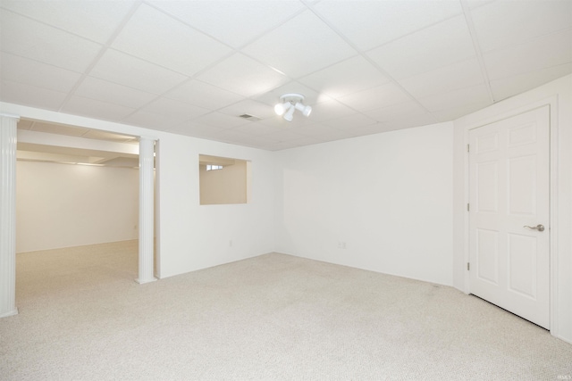 basement with a paneled ceiling and light carpet