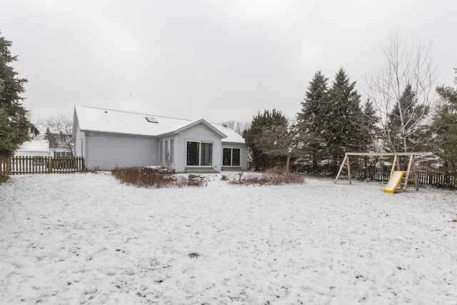 snow covered rear of property featuring a playground