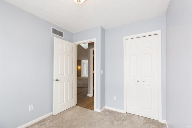 unfurnished bedroom featuring light carpet and a closet