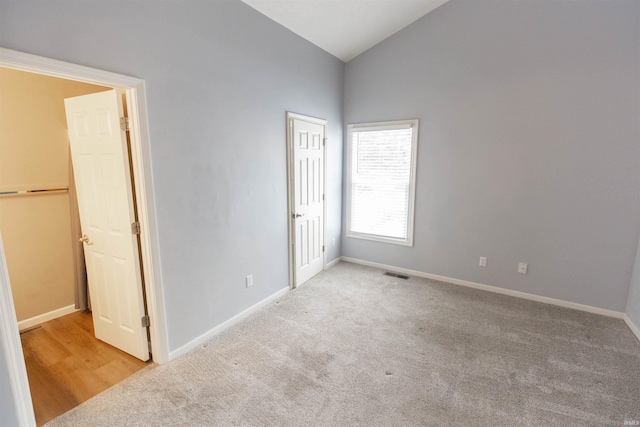 unfurnished bedroom with light carpet and vaulted ceiling