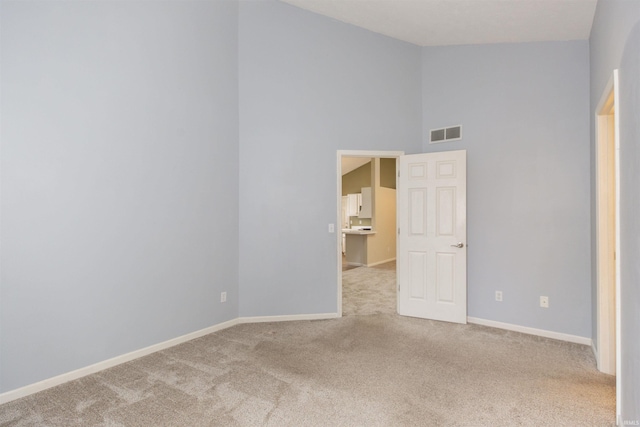 carpeted empty room featuring high vaulted ceiling