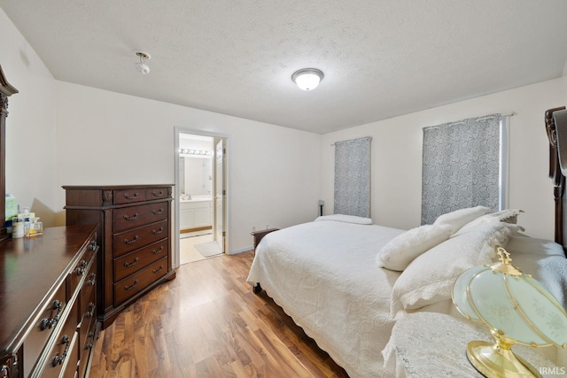 bedroom with hardwood / wood-style floors, a textured ceiling, and ensuite bath