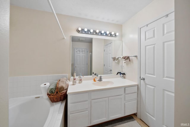 bathroom with vanity, a bath, and a textured ceiling