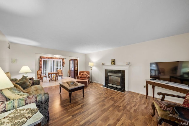 living room with a tile fireplace and hardwood / wood-style floors