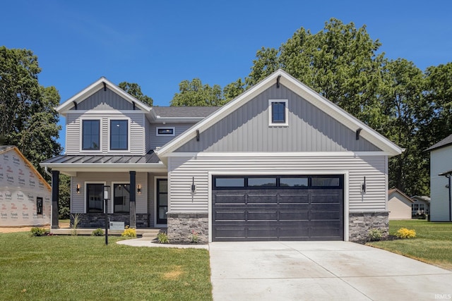 view of front of home featuring covered porch, a garage, and a front lawn