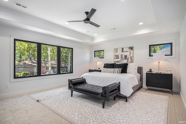 bedroom featuring ceiling fan, a raised ceiling, and light carpet