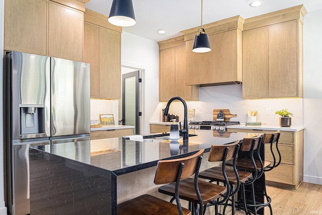 kitchen featuring light wood-type flooring, stainless steel fridge with ice dispenser, light brown cabinets, and a center island with sink