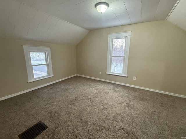 bonus room featuring lofted ceiling, carpet, visible vents, and baseboards