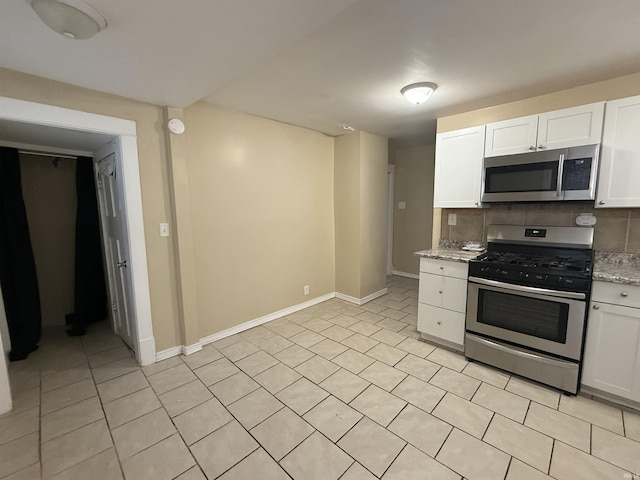 kitchen featuring baseboards, stainless steel appliances, tasteful backsplash, and white cabinets