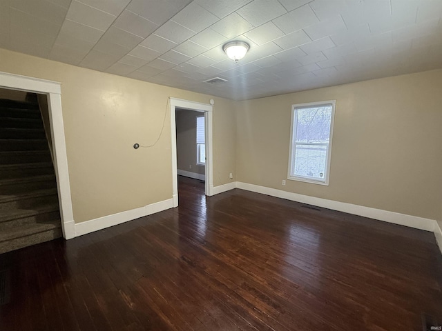 unfurnished room with visible vents, stairs, baseboards, and dark wood finished floors