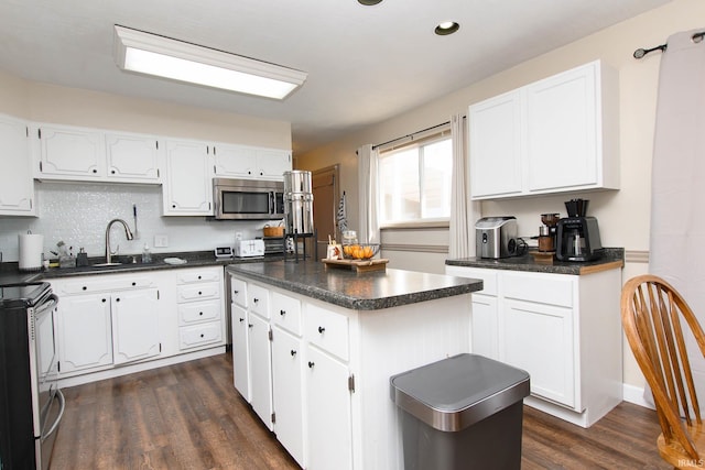 kitchen featuring white cabinets, appliances with stainless steel finishes, a kitchen island, and dark wood-type flooring