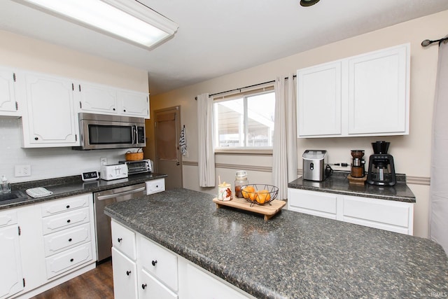 kitchen featuring backsplash, white cabinets, dark stone countertops, dark hardwood / wood-style flooring, and stainless steel appliances