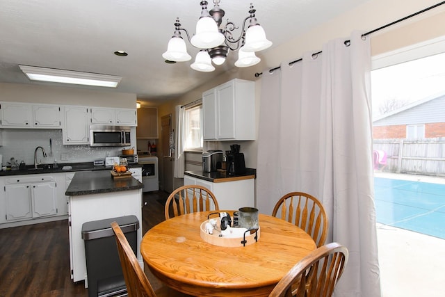 dining area featuring a notable chandelier, sink, and dark wood-type flooring