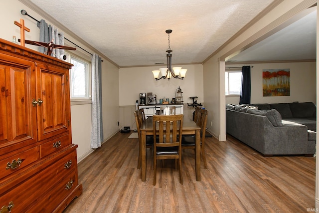 dining space featuring hardwood / wood-style floors, ornamental molding, a textured ceiling, and a chandelier