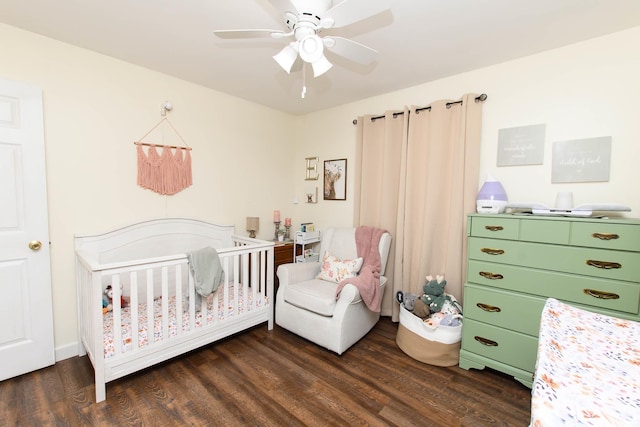 bedroom with ceiling fan, dark hardwood / wood-style flooring, and a nursery area