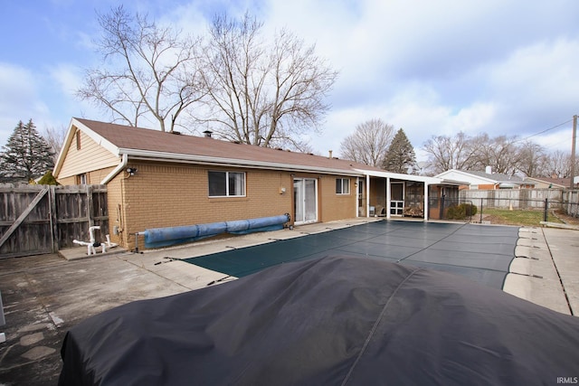 rear view of property featuring a patio area and a covered pool