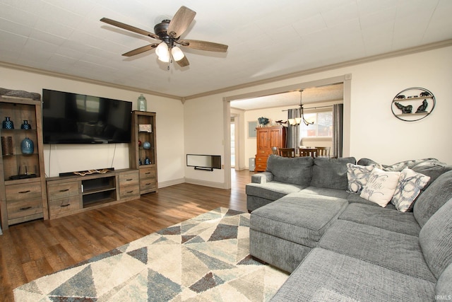 living room with dark wood-type flooring, ceiling fan with notable chandelier, and ornamental molding