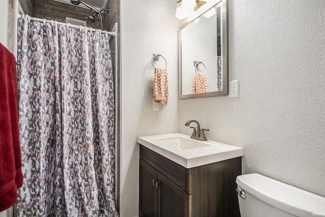 bathroom featuring vanity, toilet, and walk in shower