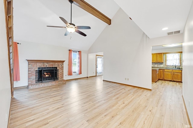 unfurnished living room with sink, beamed ceiling, high vaulted ceiling, plenty of natural light, and a fireplace