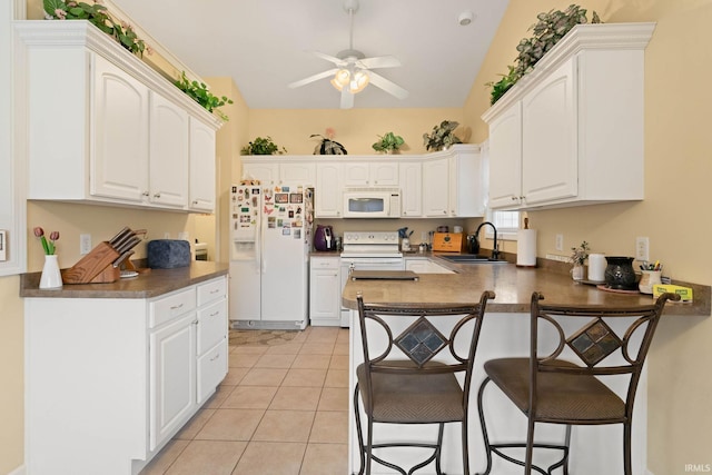 kitchen with sink, white cabinets, white appliances, and light tile patterned floors