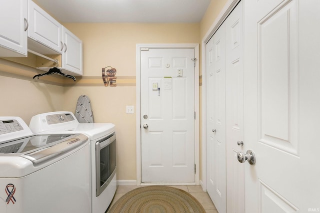 clothes washing area with washer and clothes dryer, light tile patterned flooring, and cabinets