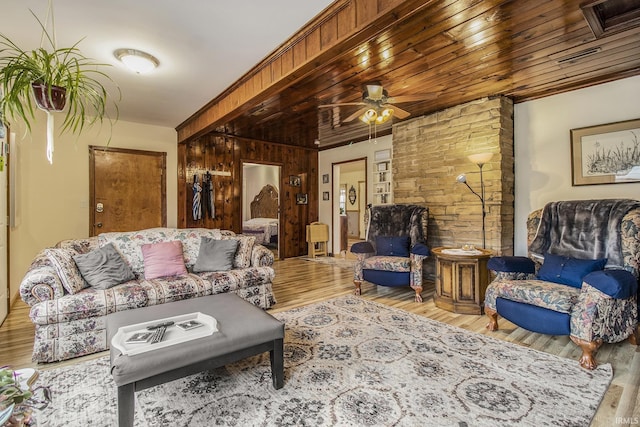 living room featuring ceiling fan, wooden walls, and light hardwood / wood-style flooring