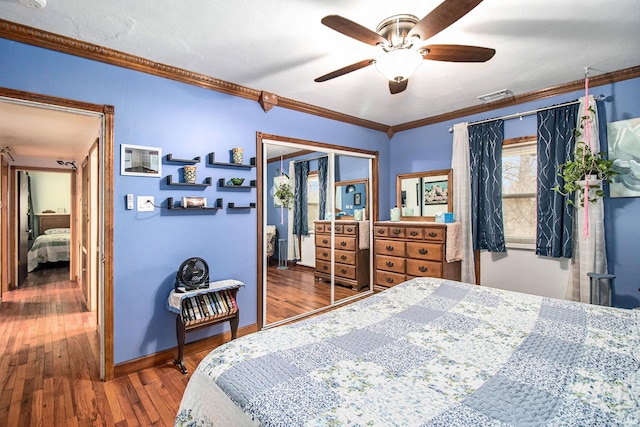 bedroom featuring hardwood / wood-style floors, ceiling fan, crown molding, and a closet