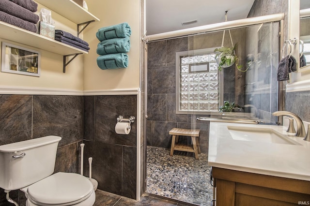 bathroom featuring vanity, toilet, tile walls, and walk in shower