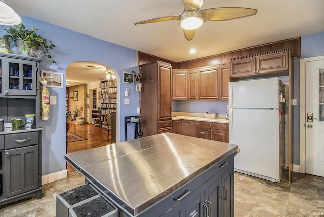 kitchen featuring white refrigerator, a kitchen island, ceiling fan, and stainless steel counters