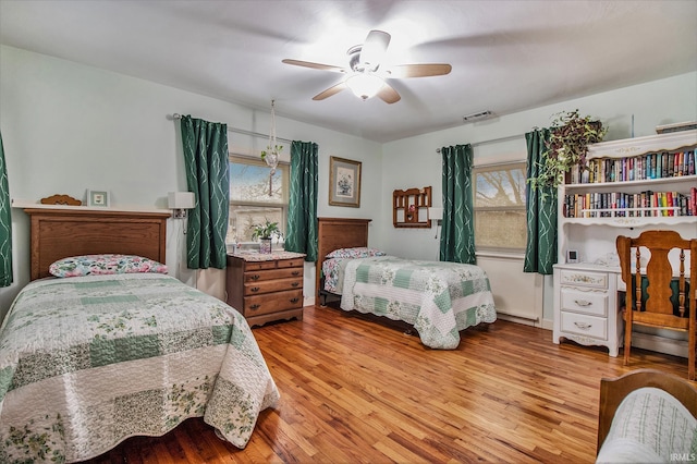 bedroom featuring hardwood / wood-style floors, ceiling fan, and multiple windows