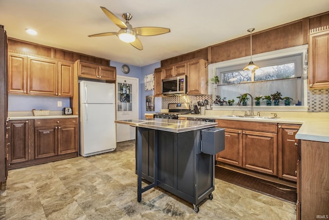 kitchen featuring tasteful backsplash, stainless steel appliances, ceiling fan, sink, and decorative light fixtures