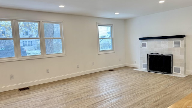 unfurnished living room with a tile fireplace and light wood-type flooring