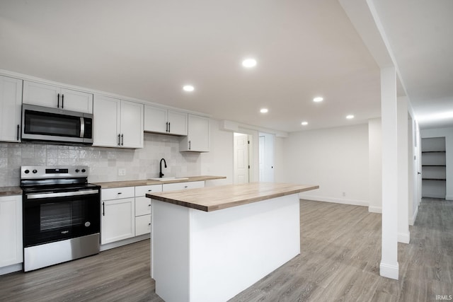 kitchen featuring white cabinets, butcher block countertops, a kitchen island, and appliances with stainless steel finishes