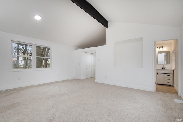 unfurnished living room featuring light carpet and lofted ceiling with beams